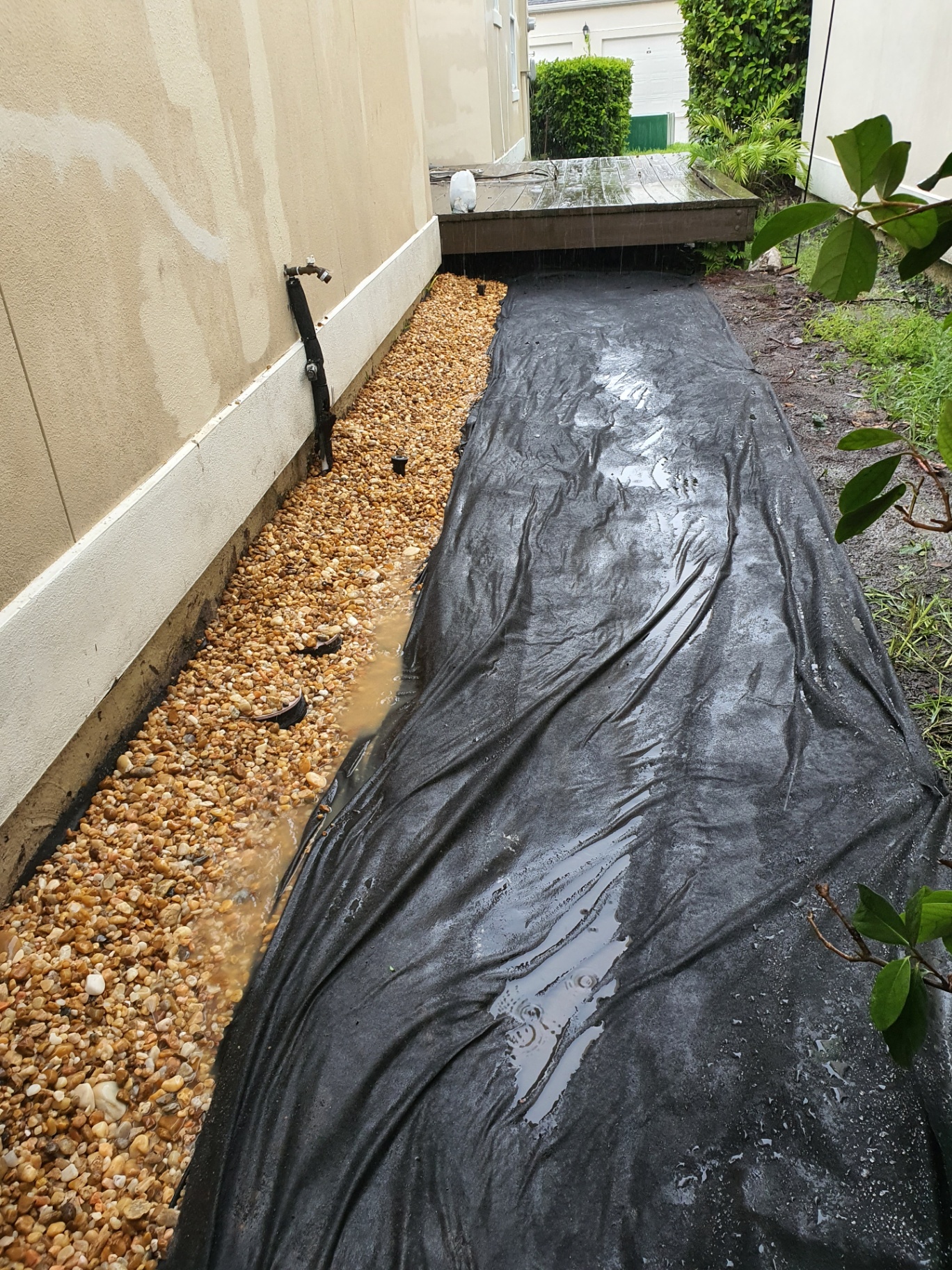 Photo of a drainage gravel channel being installed alongside a home.