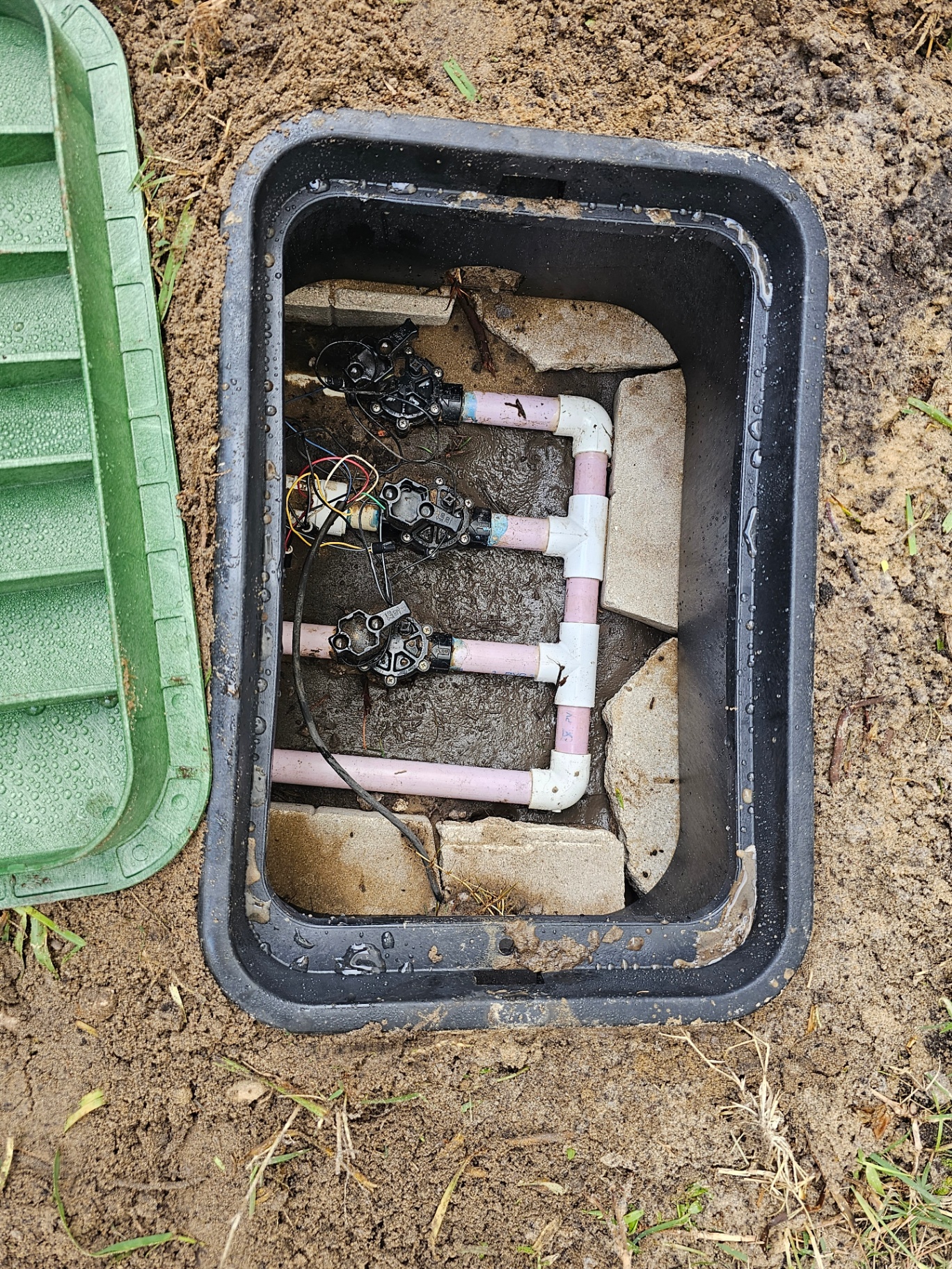 Photo of an open irrigation valve box during repair or troubleshooting.